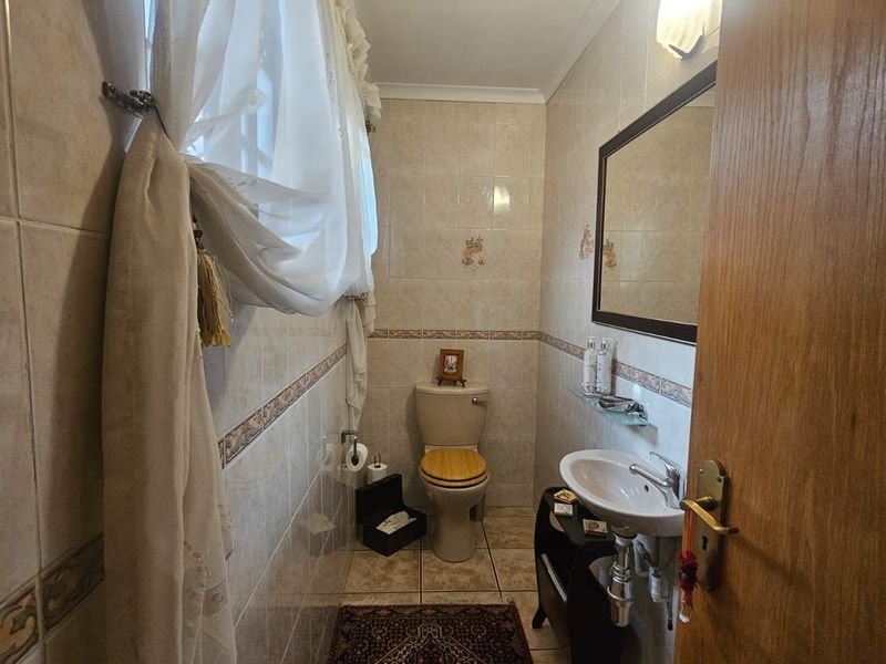 A compact guest bathroom featuring neutral wall and floor tiling, a pedestal basin, and a standard toilet.