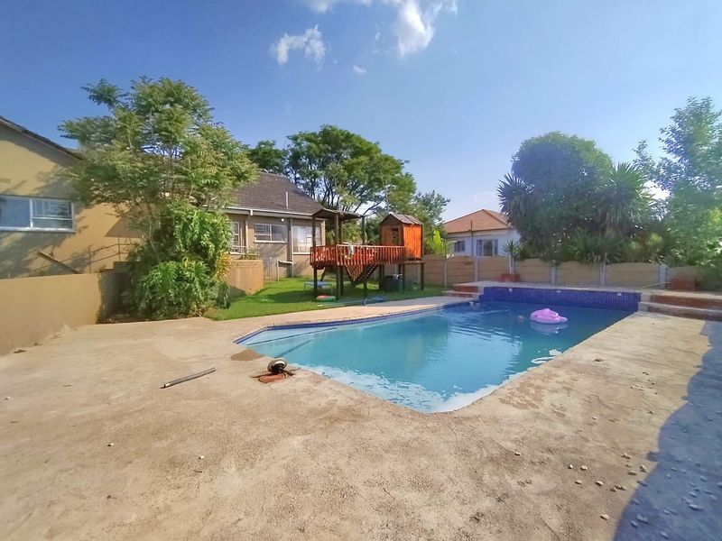 Outdoor pool area featuring a swimming pool with tiled coping, surrounded by a concrete deck and a private garden with boundary walling.
