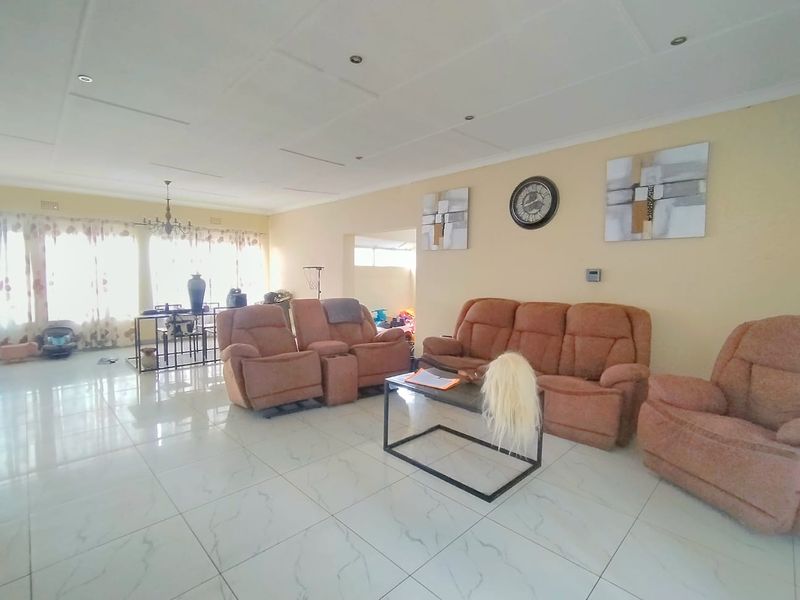 Spacious open-plan living and dining area featuring large format floor tiles and recessed ceiling lighting, offering a bright and versatile layout.