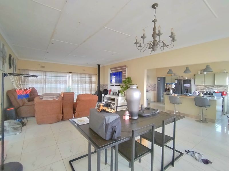 Spacious open-plan living and dining area featuring tiled floors, a freestanding fireplace, and a functional kitchen with a central island and built-in cabinetry.