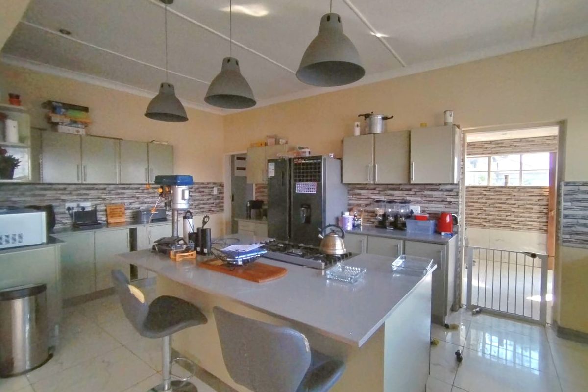 Spacious kitchen featuring a central island with a gas hob, ample cabinetry, and modern pendant lighting, offering a functional layout for cooking and dining.