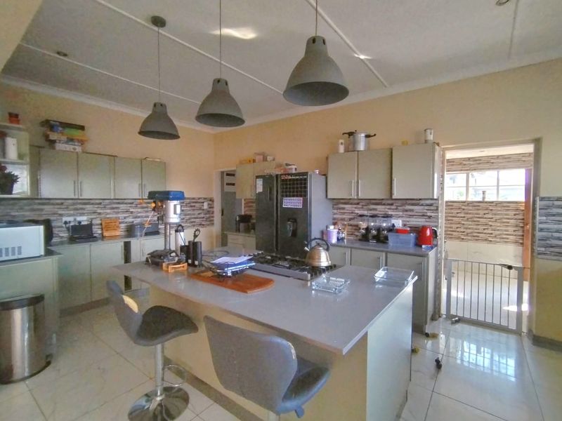 Spacious kitchen featuring a central island with a gas hob, ample cabinetry, and modern pendant lighting, offering a functional layout for cooking and dining.
