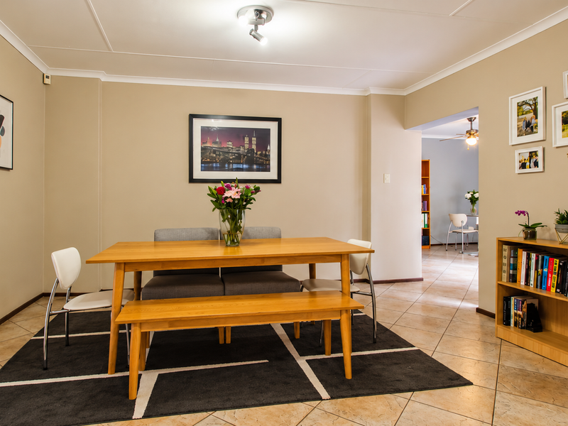 A well-maintained dining area featuring neutral wall tones, tiled flooring, and a clear transition into the adjacent living space.