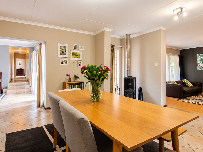 Spacious open-plan living and dining area featuring tiled flooring, a central freestanding fireplace, and seamless flow between the dining space and lounge.