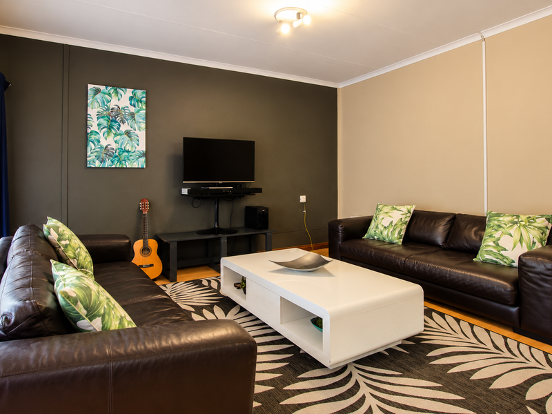 A well-maintained living room featuring laminate flooring, a feature wall, and a sliding glass door providing natural light.