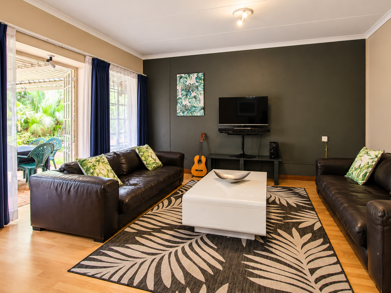 Spacious living room featuring laminate flooring, a dark accent wall, and large sliding glass doors providing direct access to the outdoor patio area.
