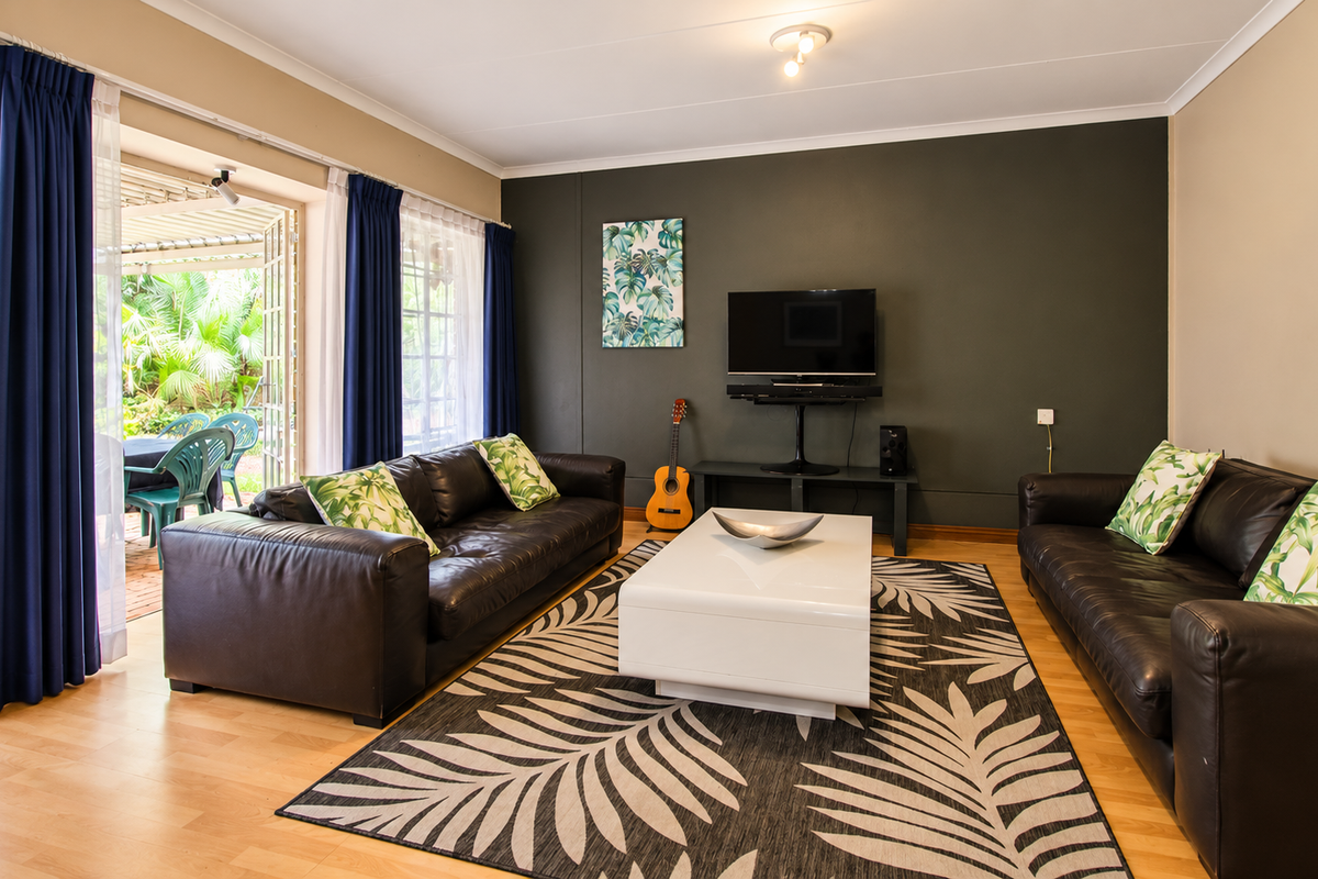 Spacious living room featuring laminate flooring, a dark accent wall, and large sliding glass doors providing direct access to the outdoor patio area.