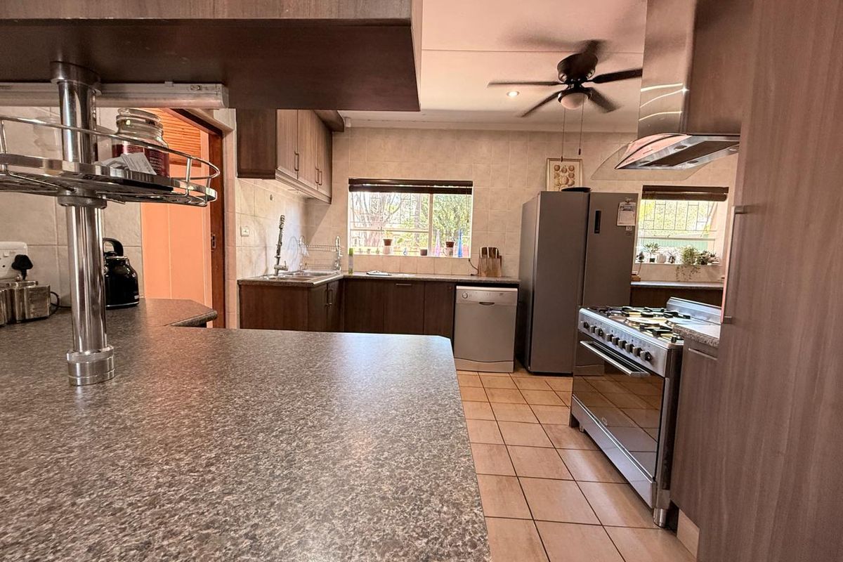 Functional kitchen featuring dark wood-look cabinetry, granite countertops, tiled flooring, and a stainless steel gas stove with an integrated extractor fan.