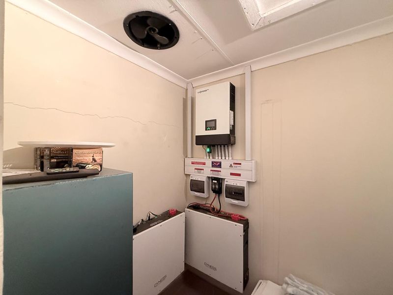 Utility space featuring a solar power inverter system with integrated lithium battery storage and electrical distribution board.