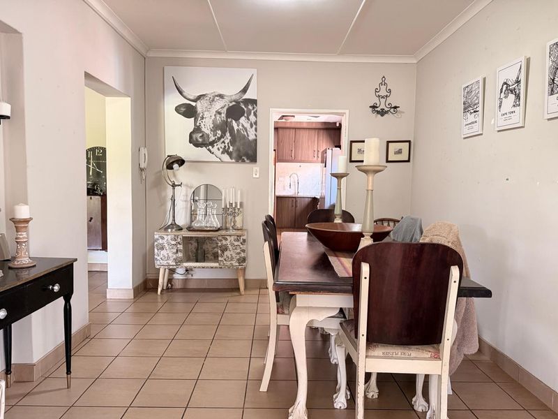 A dining room featuring tiled flooring and coved ceilings, with an open archway leading through to the kitchen area.