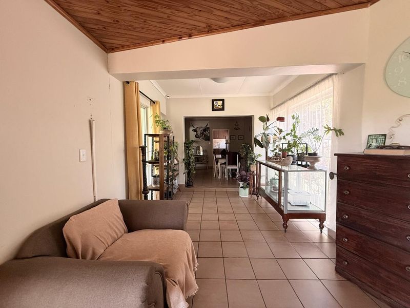 Open plan living area featuring tiled flooring and a timber-paneled ceiling, offering a spacious layout with natural light through large windows.