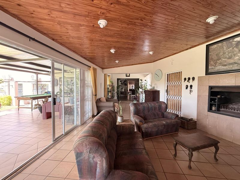 Spacious living room featuring a timber-clad ceiling, tiled flooring, and a built-in fireplace, with large sliding doors providing access to the patio.