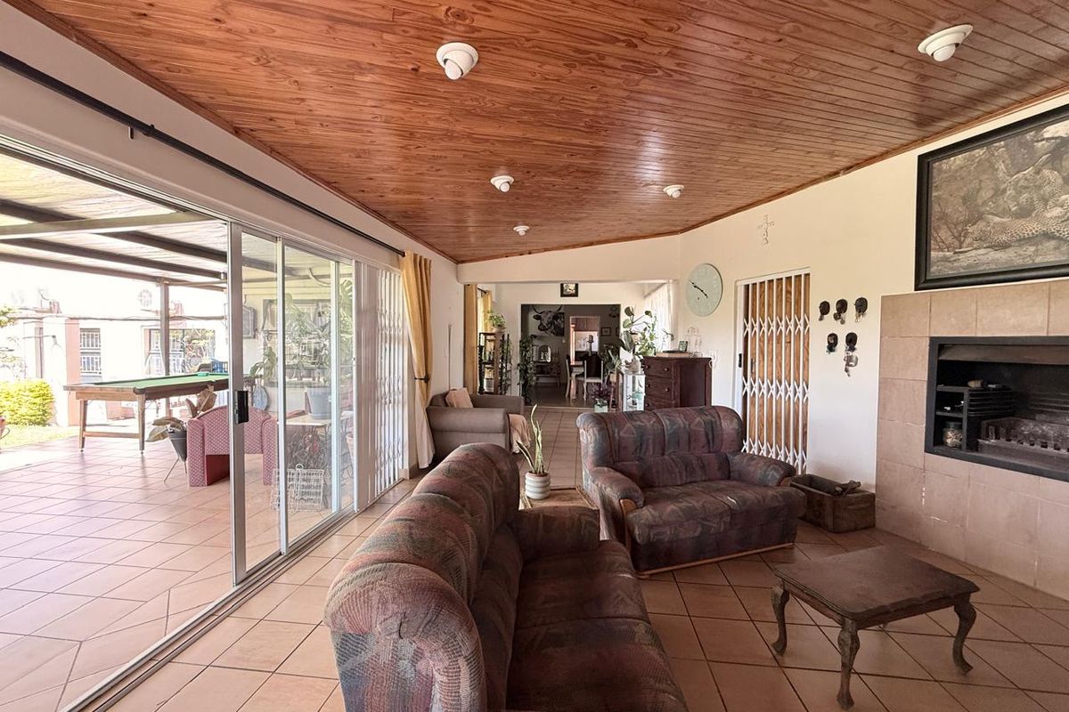 Spacious living room featuring a timber-clad ceiling, tiled flooring, and a built-in fireplace, with large sliding doors providing access to the patio.
