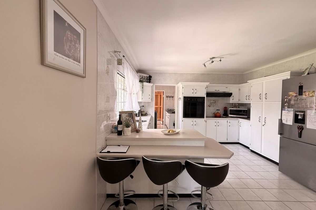 A functional kitchen featuring white cabinetry, tiled flooring, a breakfast bar, and built-in appliances, offering a practical layout for daily meal preparation.
