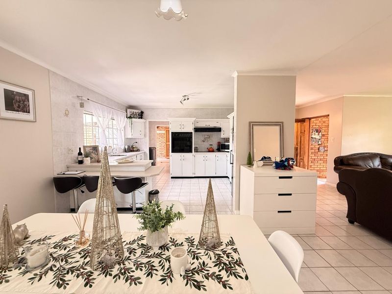 Spacious open-plan kitchen and dining area featuring white cabinetry, tiled flooring, and a functional breakfast bar layout.