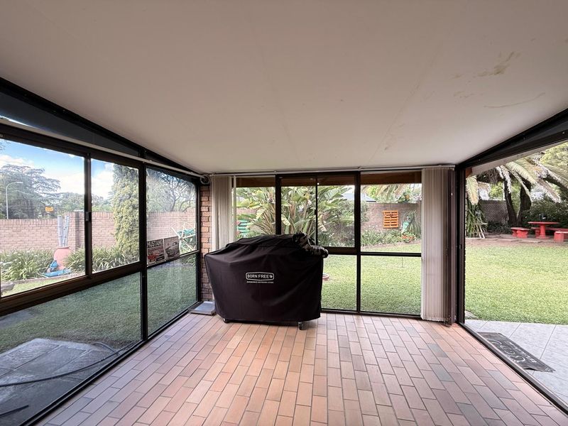 An enclosed patio area featuring tiled flooring and large glass sliding doors, offering a view of the rear garden.