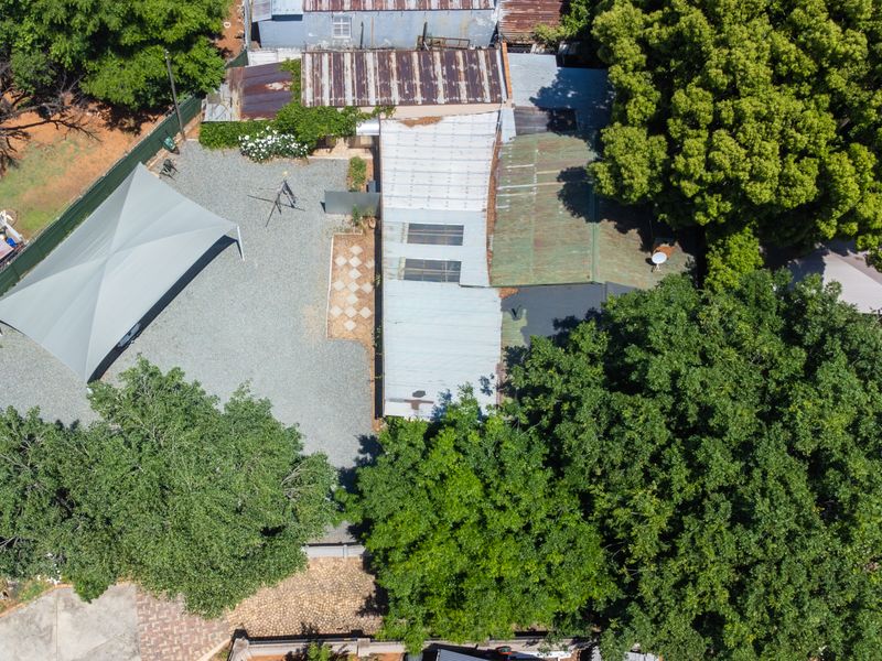 Aerial view of the property showing the main building with corrugated metal roofing, a gravel driveway, and a large shade sail structure.