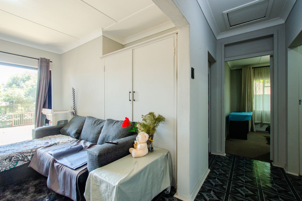 Living room area featuring built-in storage cupboards, tiled flooring, and a sliding door providing access to the exterior.