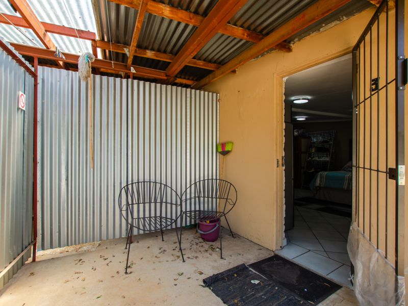 A covered outdoor patio area featuring corrugated iron walls and roof, providing a functional transition space to the interior of the home.