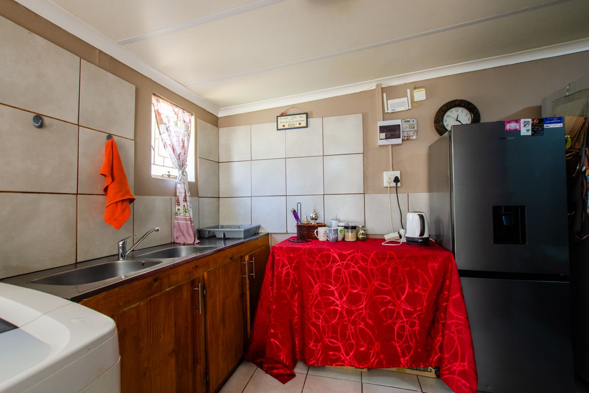 A functional kitchen featuring wooden cabinetry, a double stainless steel sink with mixer tap, and tiled splashbacks.