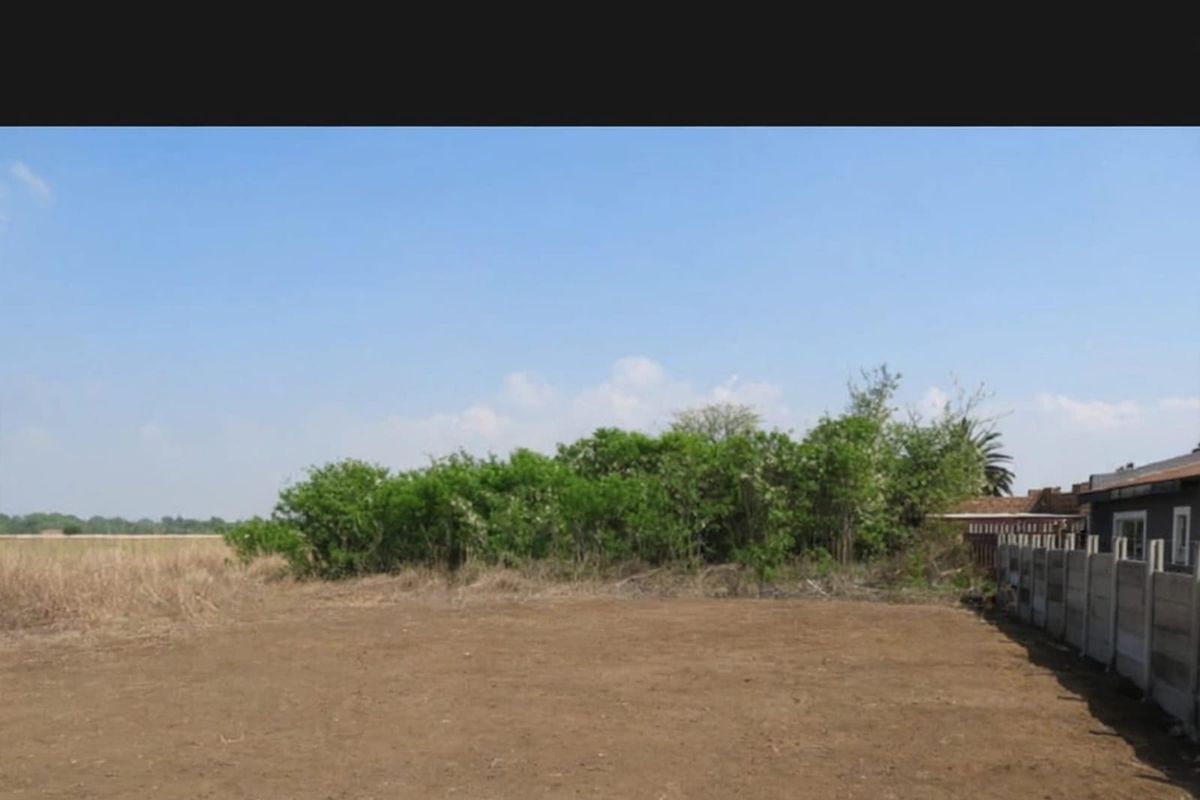 A view of the vacant residential land featuring a level plot and a precast concrete boundary wall along the side perimeter.