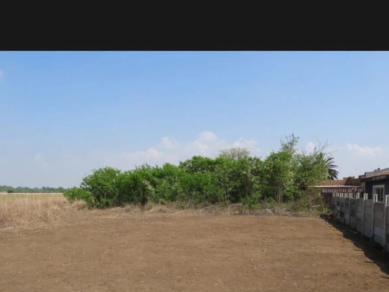 A view of the vacant residential land featuring a level plot and a precast concrete boundary wall along the side perimeter.