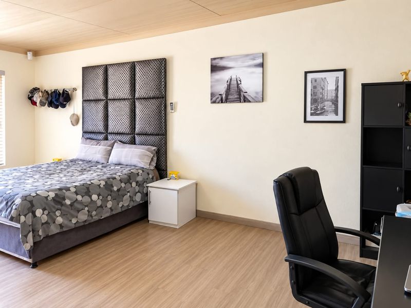 A spacious bedroom featuring laminate flooring and timber ceiling panels, offering a comfortable and functional living space.