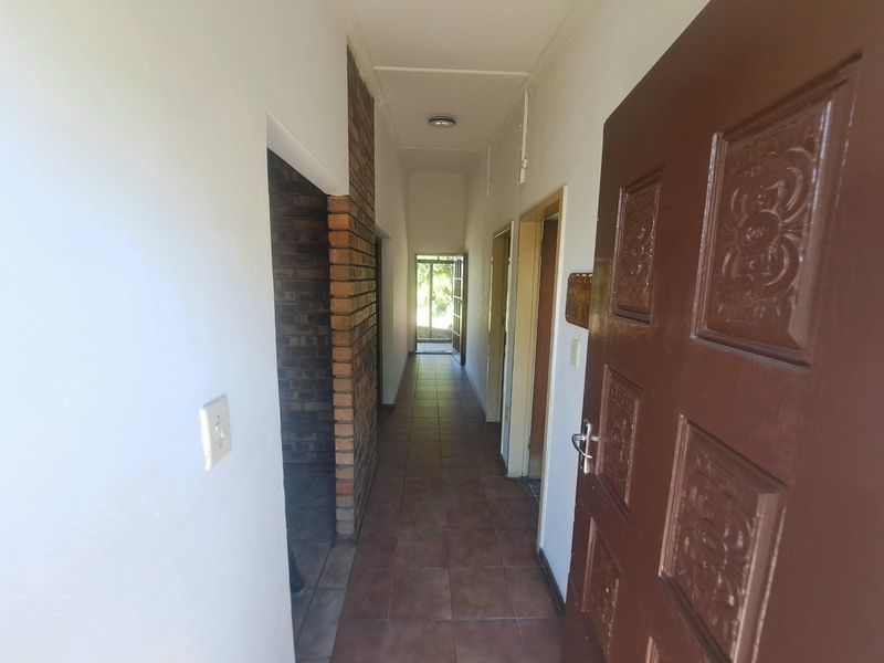 A functional hallway featuring tiled flooring, an exposed brick accent pillar, and a solid wood entrance door leading to the interior living spaces.