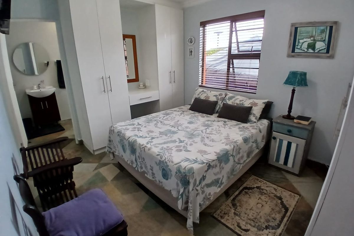 A well-maintained bedroom featuring built-in cupboards with an integrated vanity station and an adjoining en-suite bathroom with modern tiling.