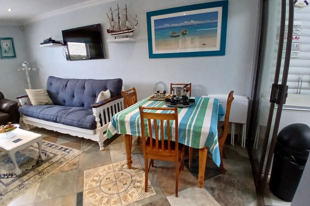 A combined living and dining area featuring tiled flooring, recessed lighting, and a sliding glass door leading to an outdoor space.
