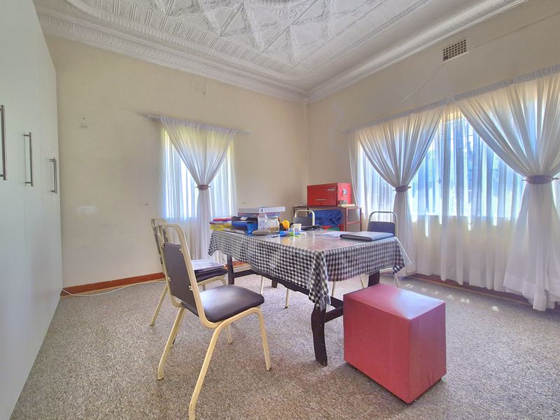 A bedroom featuring an ornate plaster ceiling, built-in cupboards, and carpeted flooring, offering a functional space with potential for cosmetic updates.
