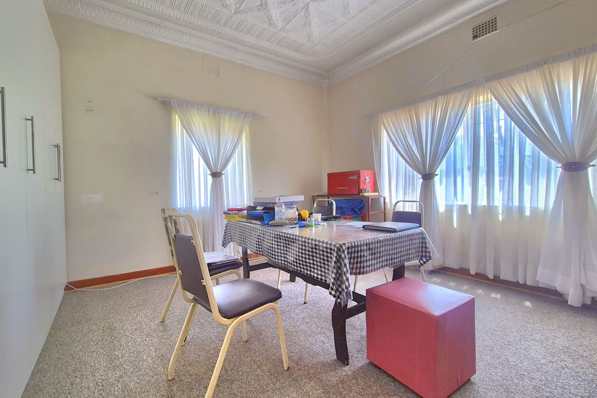 A bedroom featuring an ornate plaster ceiling, built-in cupboards, and carpeted flooring, offering a functional space with potential for cosmetic updates.