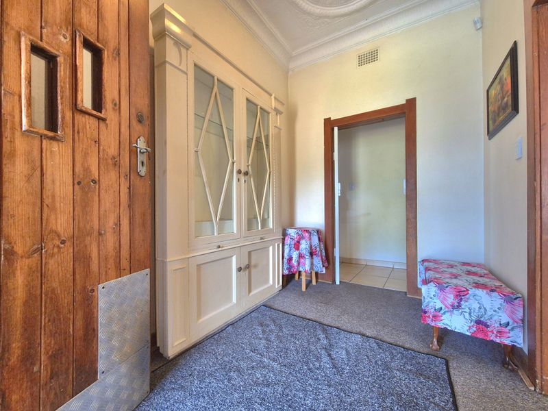 Entrance hall featuring a built-in display cabinet, ornate ceiling detailing, and timber door frames, providing a classic welcome to the home.