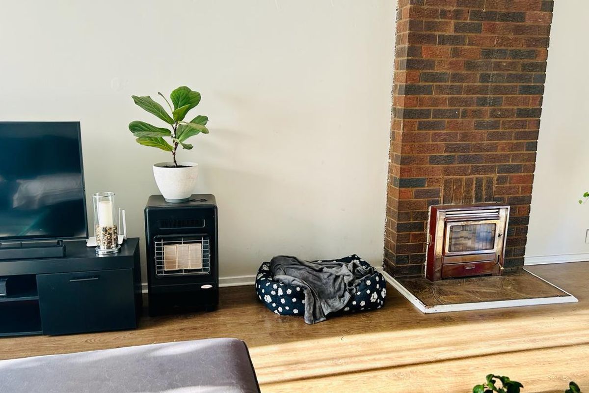 Living room featuring a prominent brick fireplace with a built-in wood-burning stove insert and durable laminate flooring.