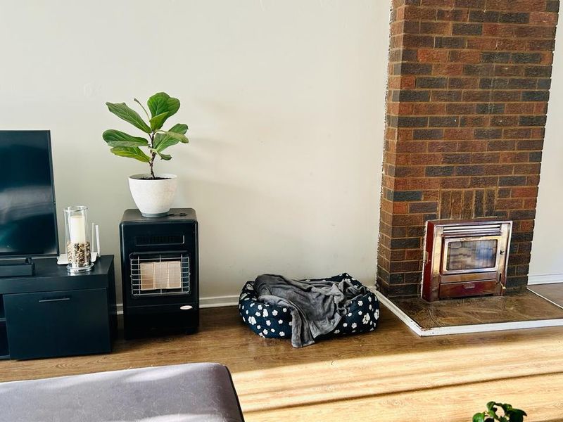 Living room featuring a prominent brick fireplace with a built-in wood-burning stove insert and durable laminate flooring.
