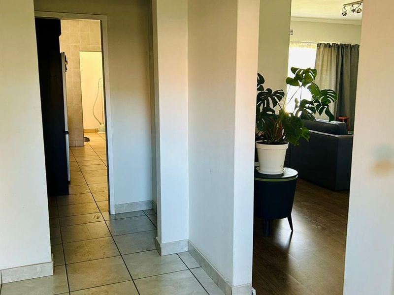 A functional hallway connecting the living area and kitchen, featuring a mix of tiled and laminate flooring throughout the transition space.