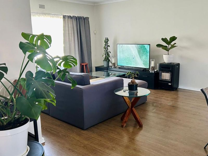 A comfortable living room featuring laminate flooring and a built-in gas heater, offering a functional and inviting space for relaxation.