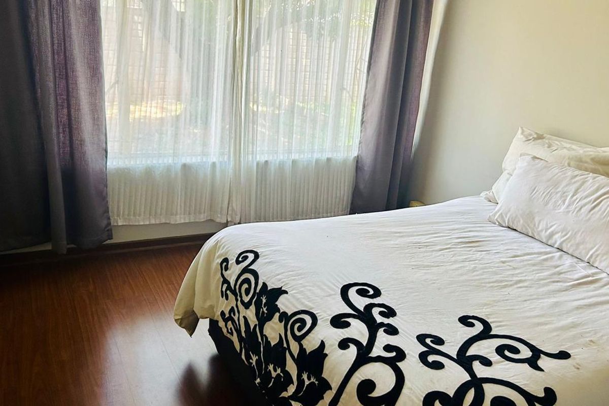A bedroom featuring laminate flooring and large windows with installed curtain tracks, providing natural light.