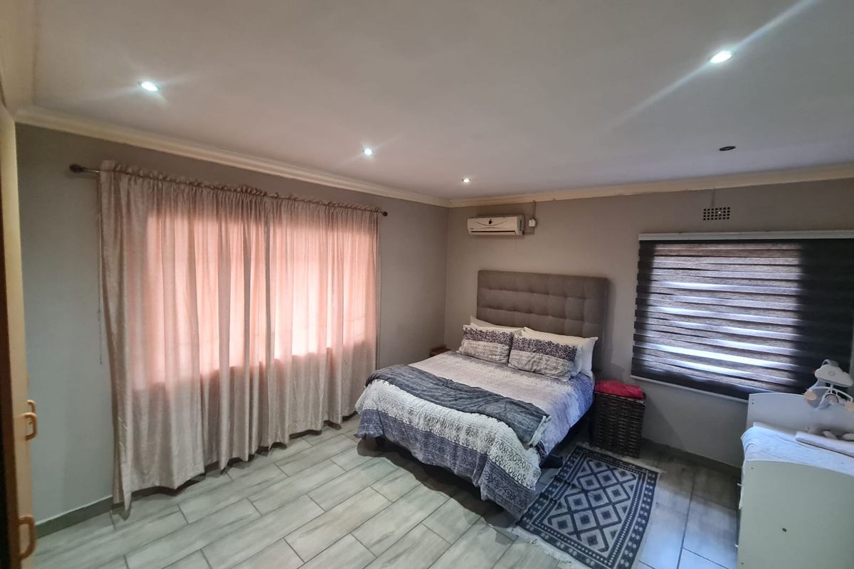 A well-maintained bedroom featuring tiled flooring, recessed downlighting, an integrated air conditioning unit, and neutral wall finishes.