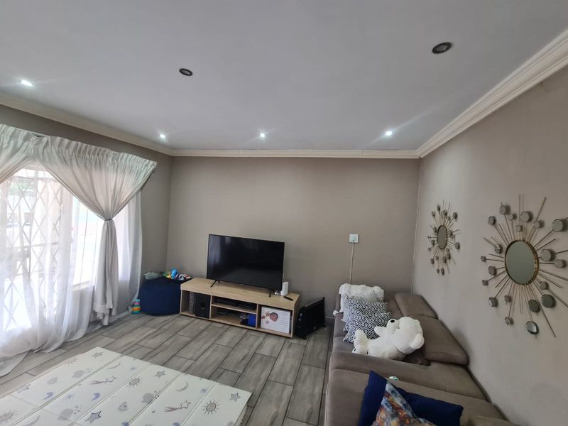 A comfortable living room featuring tiled flooring, recessed downlighting, and decorative crown molding, providing a neutral and functional space.