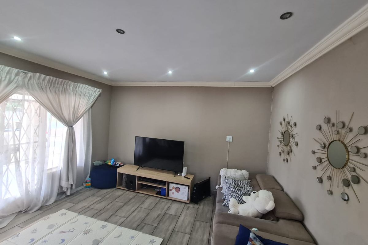 A comfortable living room featuring tiled flooring, recessed downlighting, and decorative crown molding, providing a neutral and functional space.