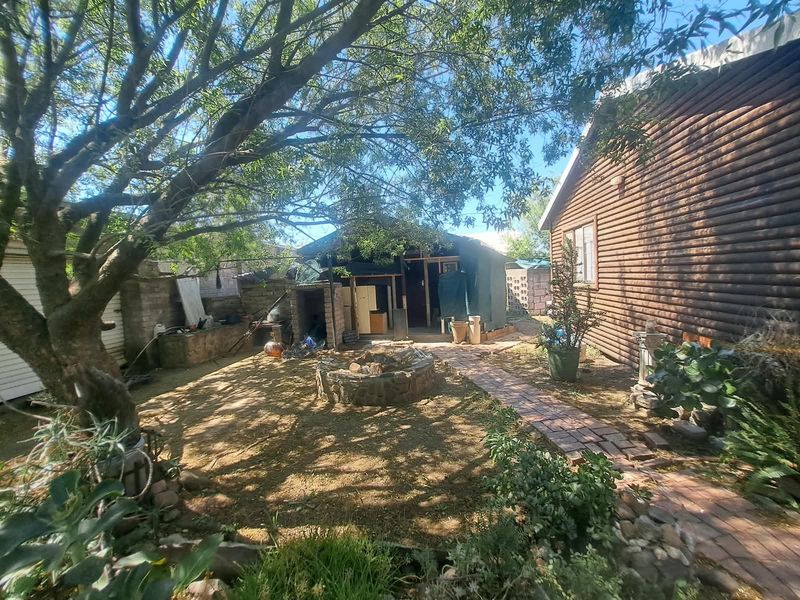 Rear garden area featuring a brick pathway, stone fire pit, and log cabin style exterior walling.