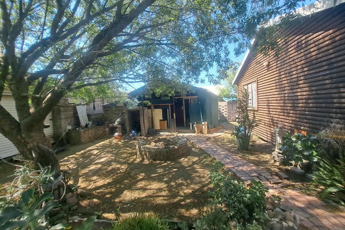 Rear garden area featuring a brick pathway, stone fire pit, and log cabin style exterior walling.