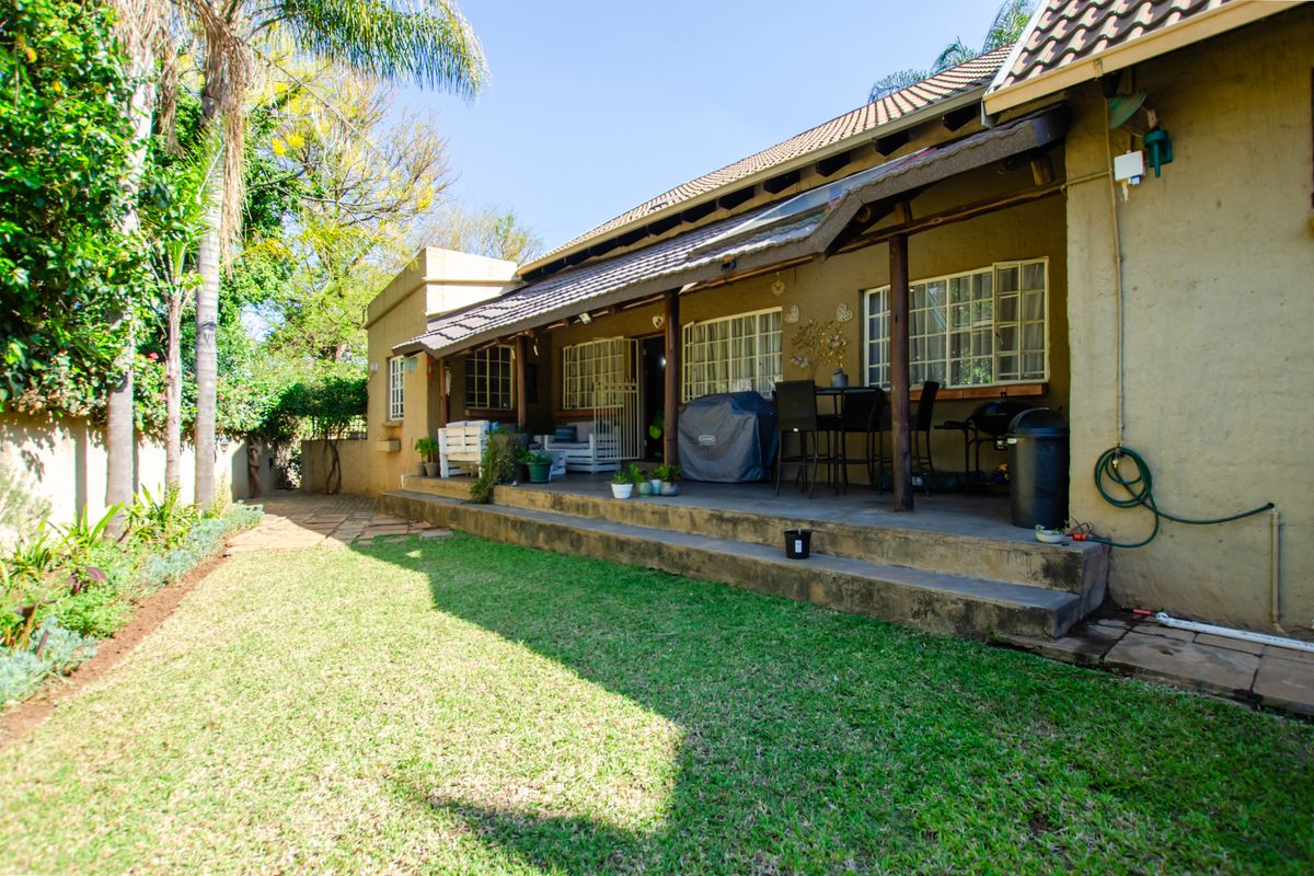 Rear view of the property featuring a covered patio area, concrete steps, and a well-maintained garden space.
