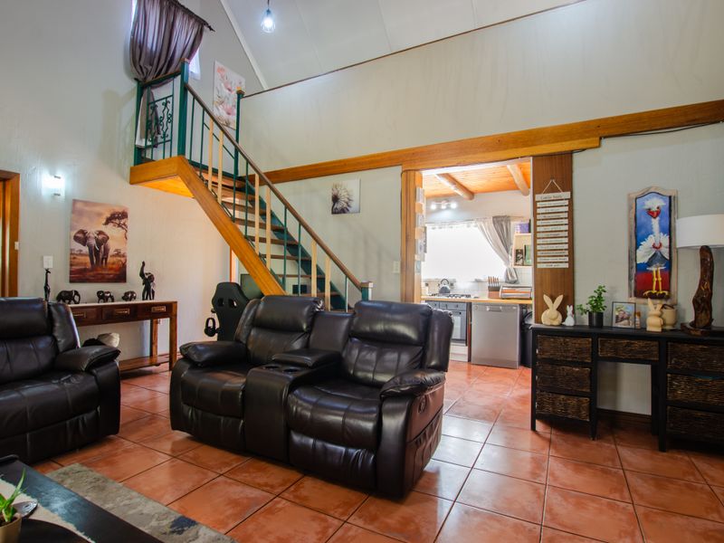 Open plan living area featuring tiled flooring, a staircase leading to a mezzanine level, and an adjacent kitchen with built-in cabinetry and appliances.