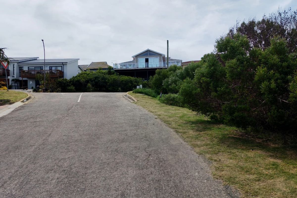 A street view showing the asphalt road, grass verge, and surrounding residential properties in a quiet neighborhood setting.