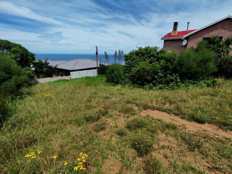 A vacant residential plot featuring a gentle slope and scenic coastal views, situated in a developed neighborhood.