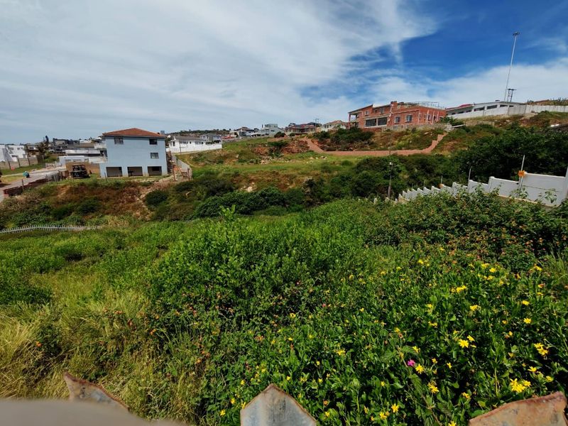 A view of a sloped, undeveloped residential plot featuring natural vegetation and surrounding neighborhood properties.