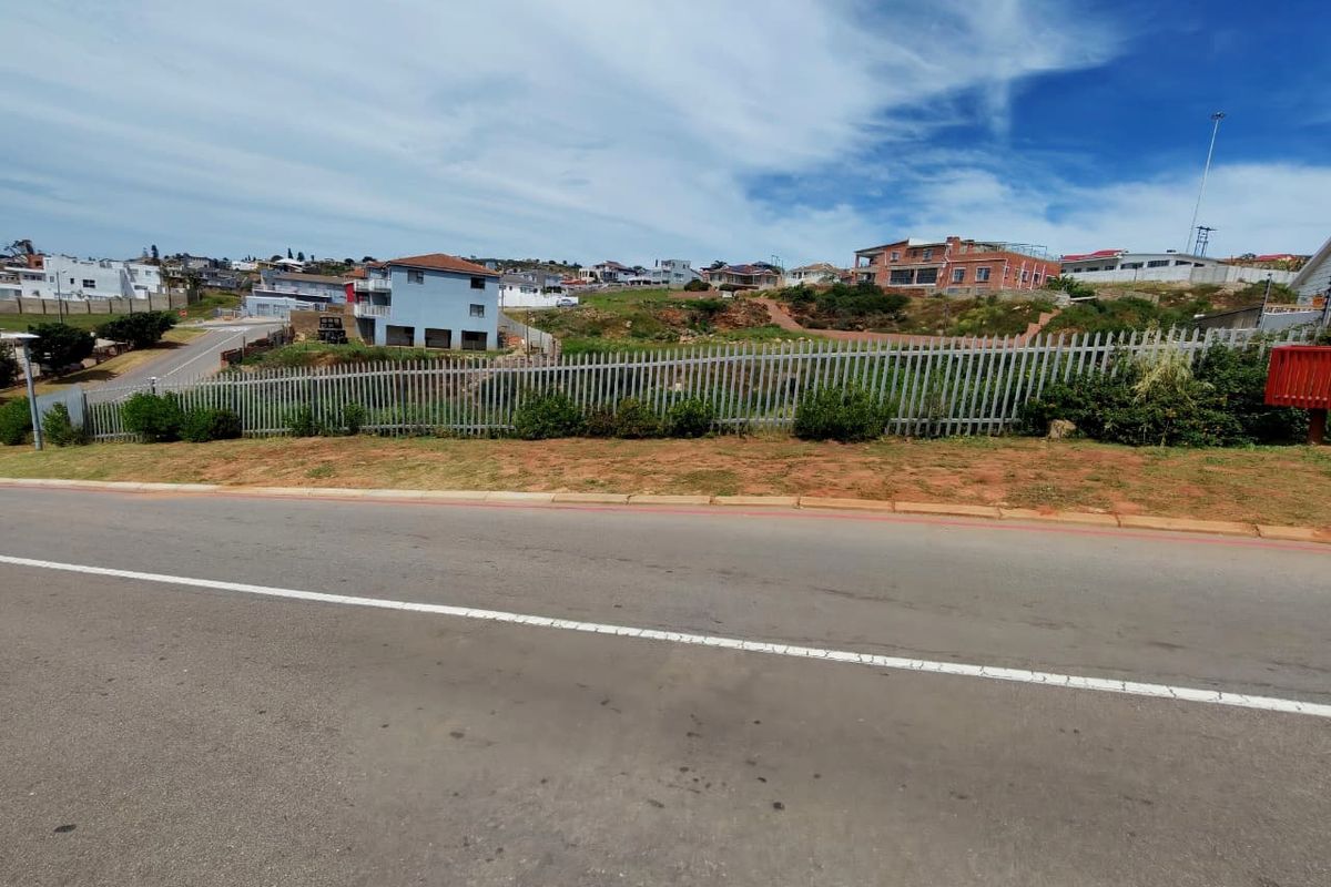 Street view of a vacant residential plot secured with metal palisade fencing, situated in an established neighborhood.