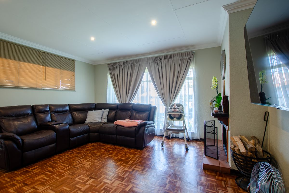 A comfortable living room featuring warm parquet flooring, a traditional fireplace, and recessed downlighting, creating a cozy and inviting atmosphere.